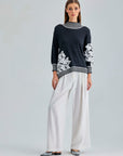 Elegant Leti Sweater featuring white floral accents along the sleeves and edges for a refined look